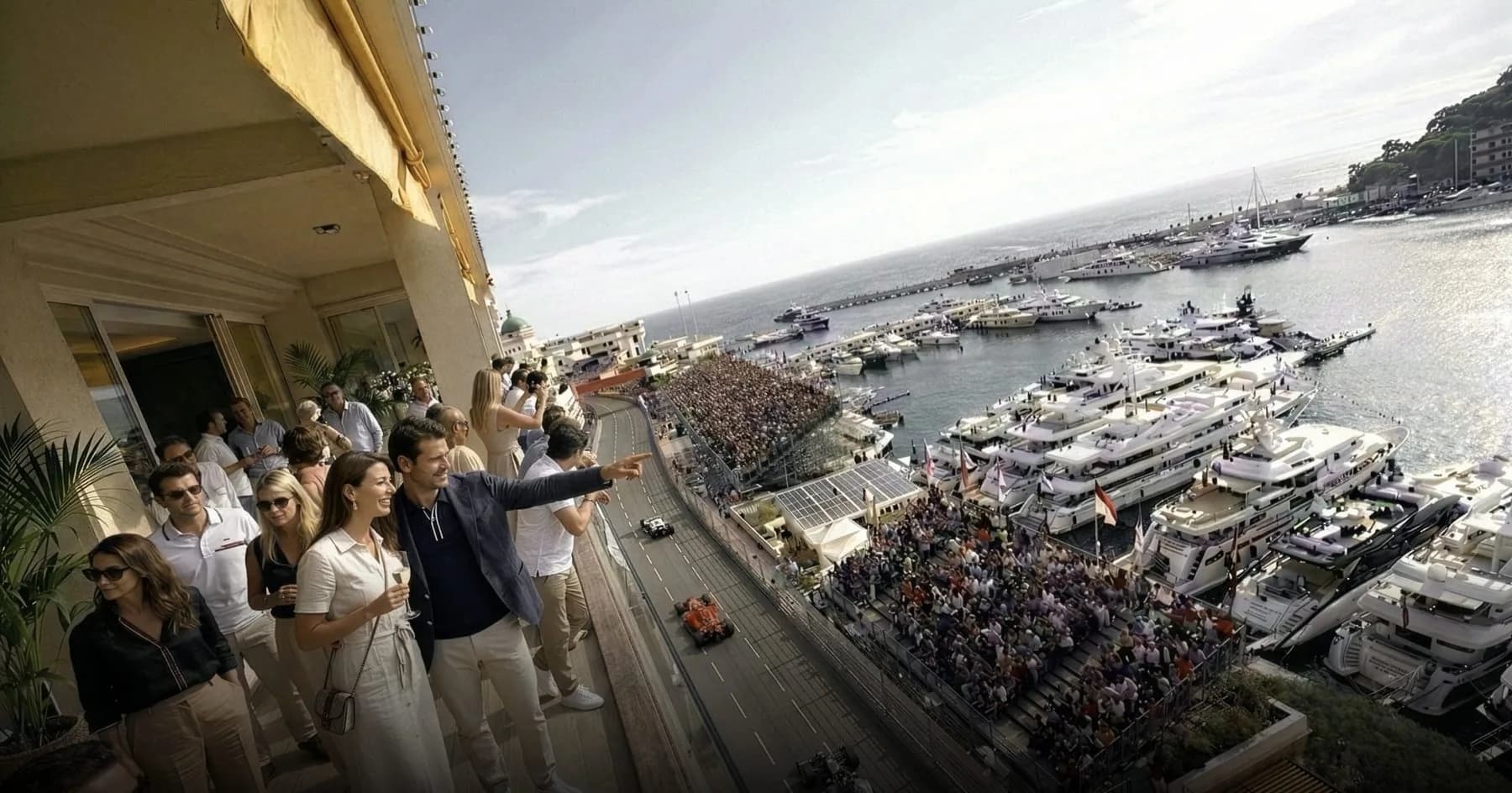 Invités sur un balcon qui regardent le circuit et le port de Monaco pendant le Grand Prix